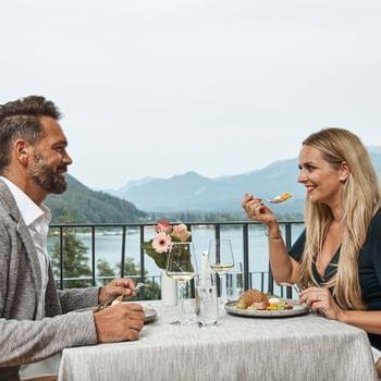 Ristorante e bar Coppia che cena su un balcone con vista panoramica su lago e montagne